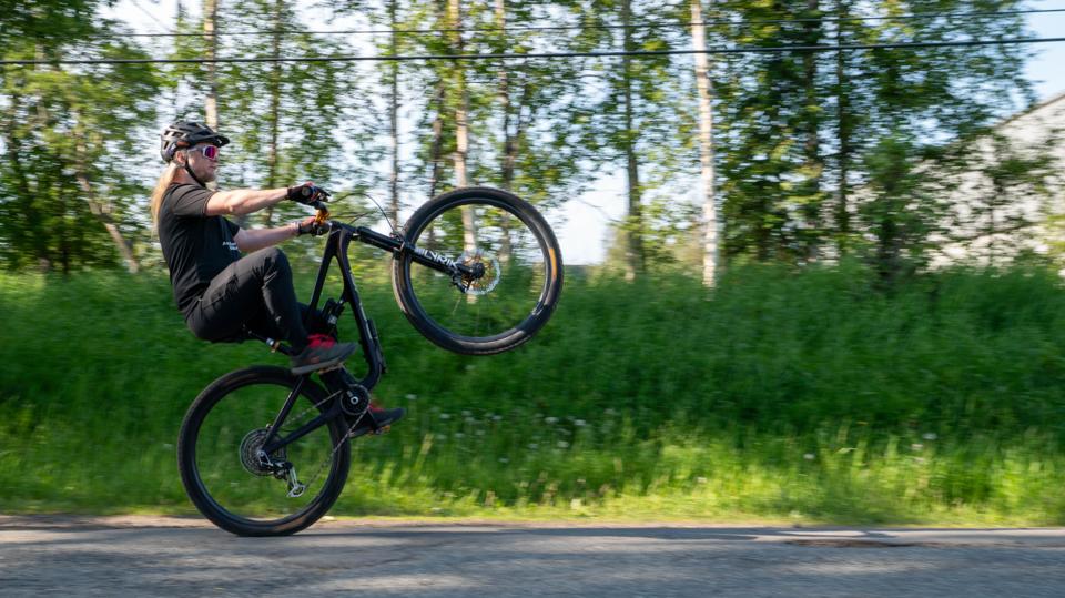 Biker doing a wheelie with trees behind